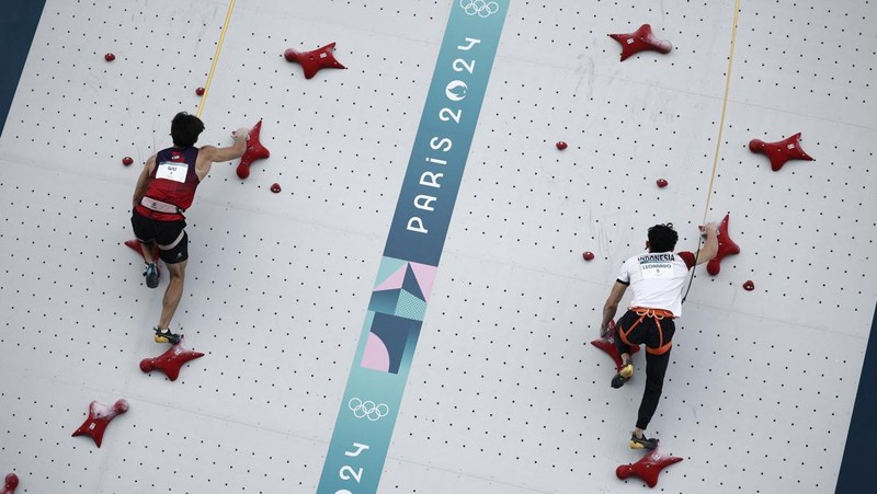 Veddriq Leonardo mengibarkan bendera Indonesia usai berhasil meraih medali emas pertama buat Indonesia usai mengalahkan Wu Peng pada final nomor speed panjat tebing di Le Boruget Climbing Venue, Kamis (8/8/2024). (REUTERS/Benoit Tessier)