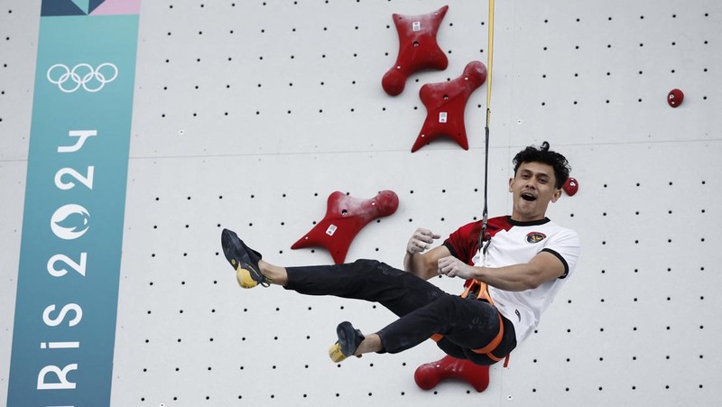 Veddriq Leonardo mengibarkan bendera Indonesia usai berhasil meraih medali emas pertama buat Indonesia usai mengalahkan Wu Peng pada final nomor speed panjat tebing di Le Boruget Climbing Venue, Kamis (8/8/2024). (REUTERS/Benoit Tessier)