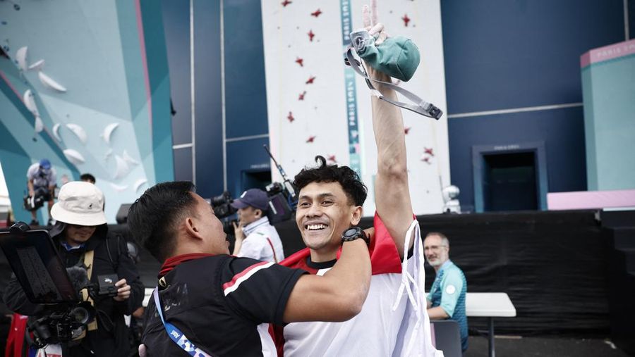 Veddriq Leonardo mengibarkan bendera Indonesia usai berhasil meraih medali emas pertama buat Indonesia usai mengalahkan Wu Peng pada final nomor speed panjat tebing di Le Boruget Climbing Venue, Kamis (8/8/2024). (REUTERS/Benoit Tessier)