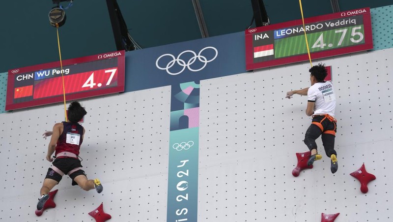 Veddriq Leonardo mengibarkan bendera Indonesia usai berhasil meraih medali emas pertama buat Indonesia usai mengalahkan Wu Peng pada final nomor speed panjat tebing di Le Boruget Climbing Venue, Kamis (8/8/2024). (REUTERS/Benoit Tessier)