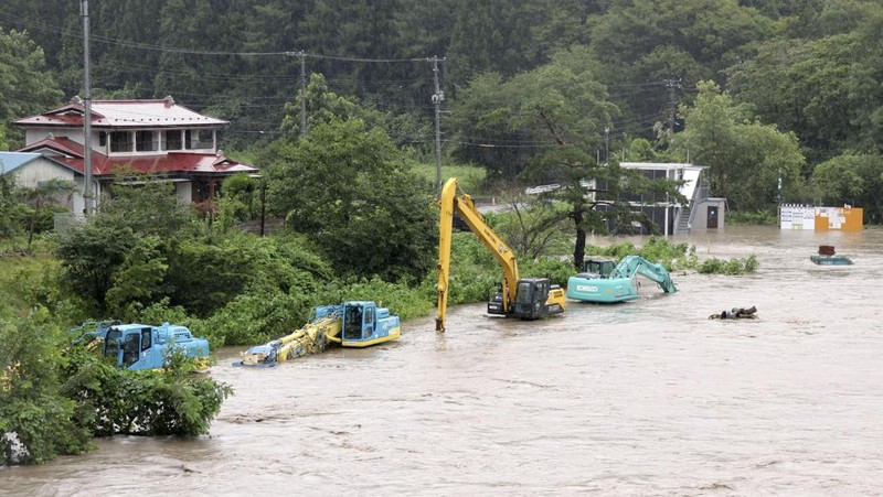 A man walks past a flooded road in the wake of 