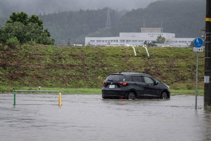 A man walks past a flooded road in the wake of 
