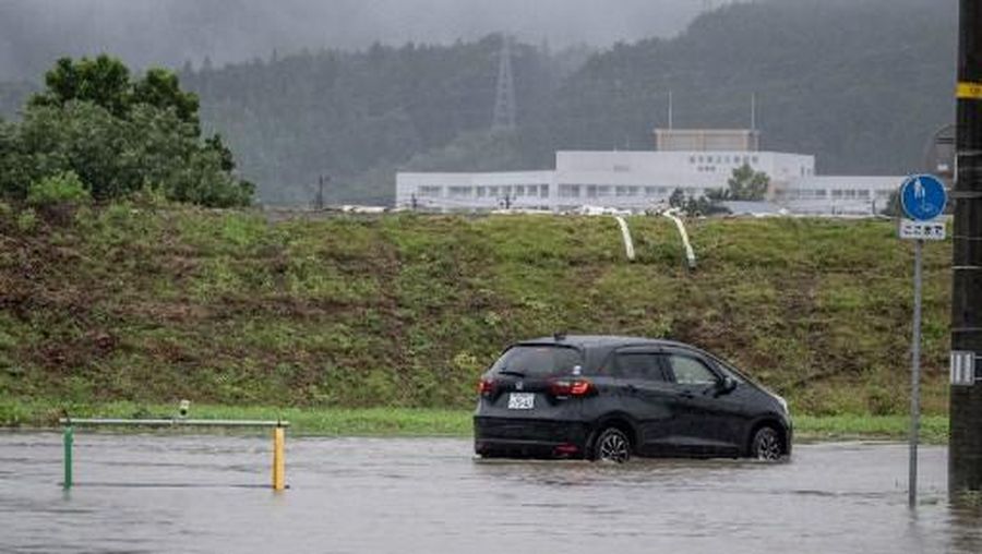 A man walks past a flooded road in the wake of 