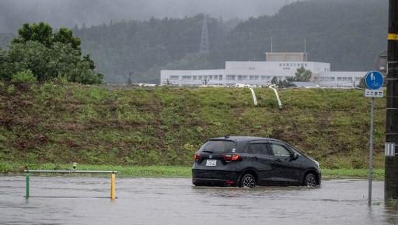 A man walks past a flooded road in the wake of 