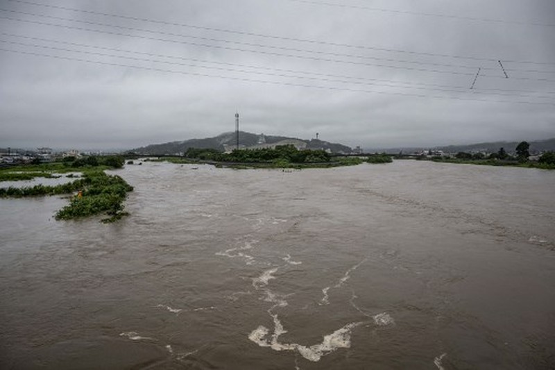 A man walks past a flooded road in the wake of 