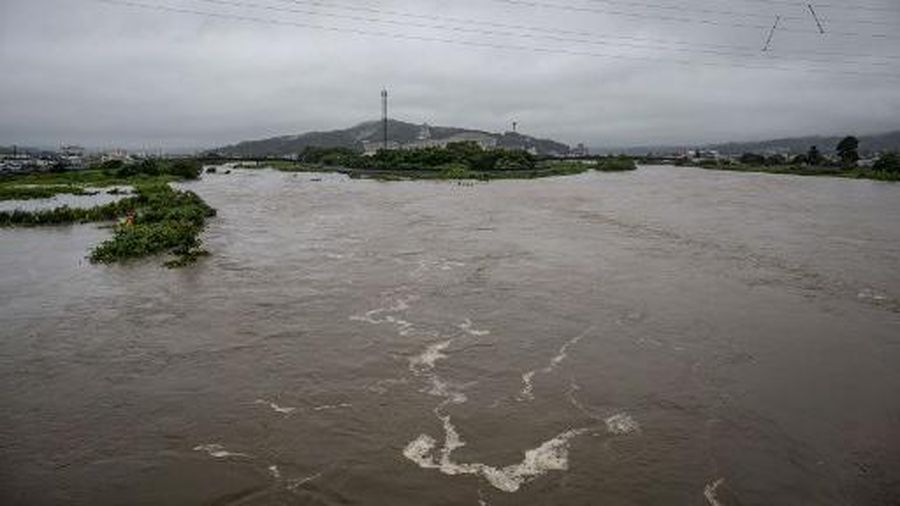 A man walks past a flooded road in the wake of 
