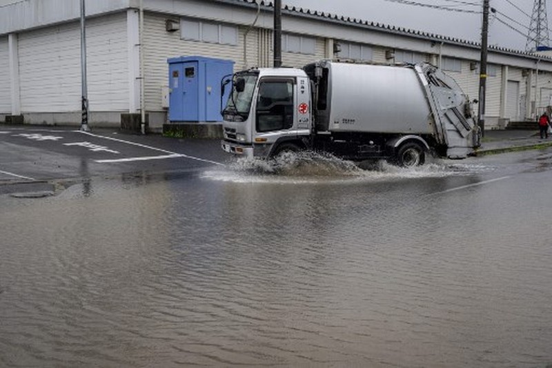 A man walks past a flooded road in the wake of 