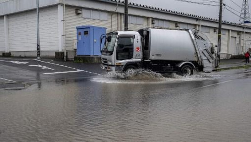 A man walks past a flooded road in the wake of 