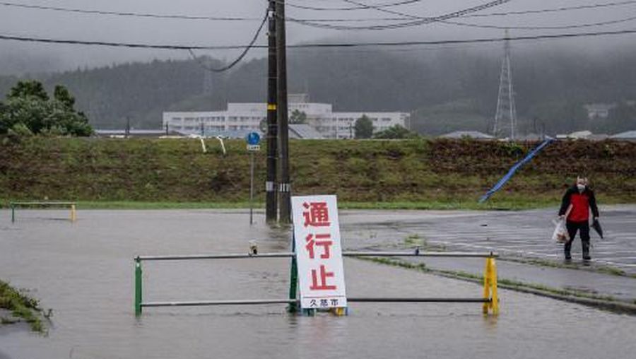 A man walks past a flooded road in the wake of 