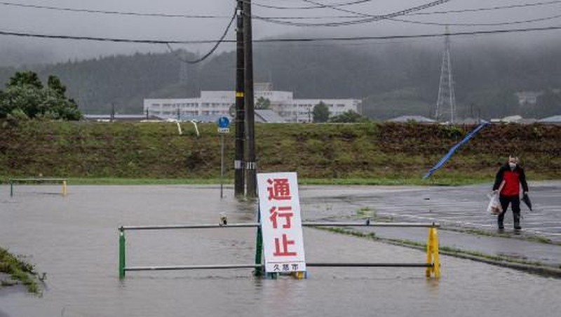 A man walks past a flooded road in the wake of 
