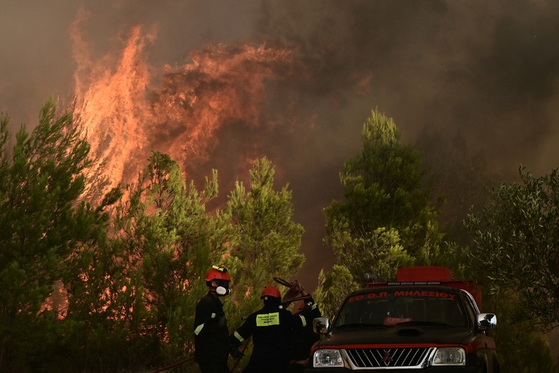 Penduduk setempat berdiri di samping mobil saat asap mengepul dari kebakaran hutan yang terjadi di desa Varnavas, dekat Athena, Yunani, 11 Agustus 2024. Penduduk setempat berdiri di samping mobil saat asap mengepul dari kebakaran hutan yang terjadi di desa Varnavas, dekat Athena, Yunani, 11 Agustus 2024. (REUTERS/Hilary Swift)