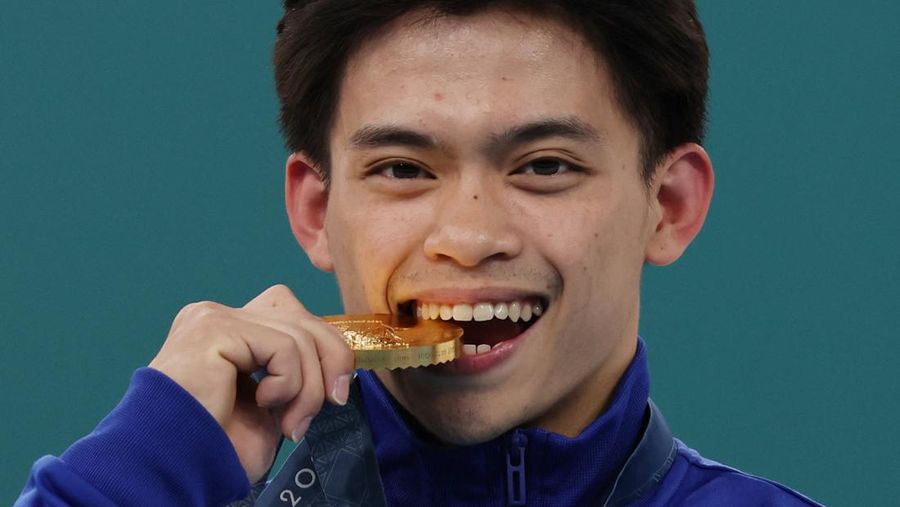 Atlet Lompat Putra Filipina, Carlos Edriel Yulo peraih medali emas di Olimpiade Paris 2024 merayakan di podium dengan medalinya. (REUTERS/Mike Blake)