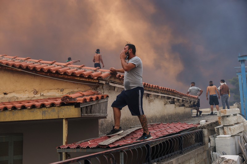 Sebuah bangunan sekolah menengah atas dan pusat kebugarannya terlihat terbakar saat kebakaran hutan melanda Nea Penteli, dekat Athena, Yunani, 12 Agustus 2024. (REUTERS/Alexandros Avramidis)