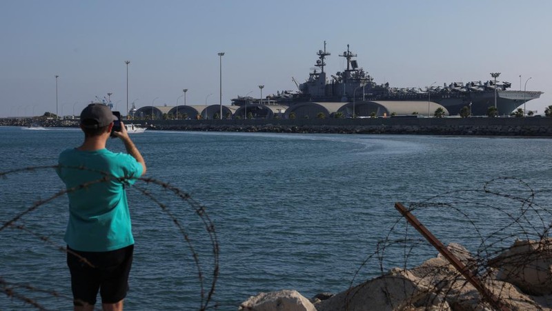 Seorang pria mengambil foto kapal serbu amfibi USS Wasp (LHD-1), saat berlabuh di pelabuhan Limassol, di tengah meningkatnya ketegangan di Timur Tengah, di Limassol, Siprus, 10 Agustus 2024. (REUTERS/Stelios Misinas)