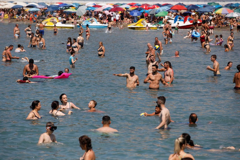 Orang-orang menikmati laut di perairan dangkal saat suhu mendekati 40 derajat Celsius di Ulcinj, Montenegro, 13 Agustus 2024. (REUTERS/Stevo Vasiljevic)
