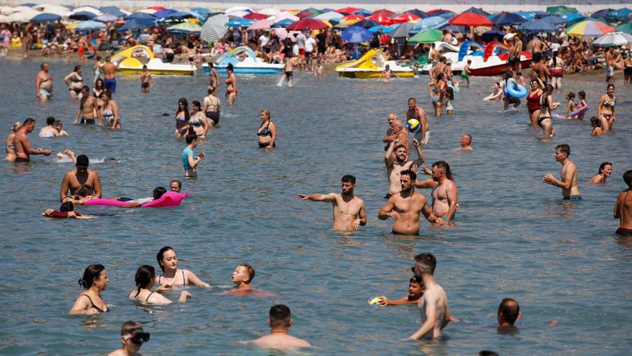 Orang-orang menikmati laut di perairan dangkal saat suhu mendekati 40 derajat Celsius di Ulcinj, Montenegro, 13 Agustus 2024. (REUTERS/Stevo Vasiljevic)