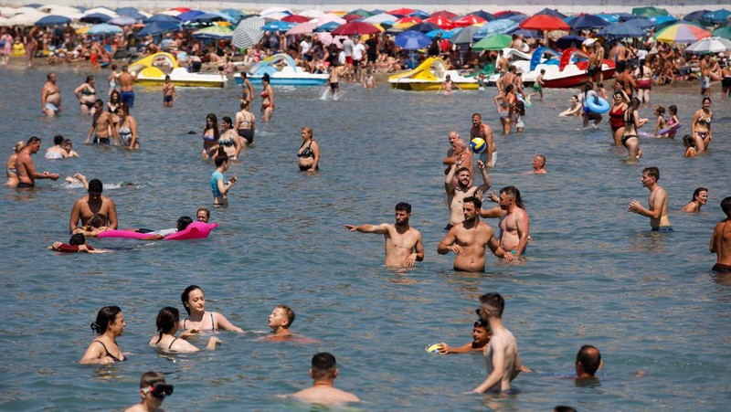 Orang-orang menikmati laut di perairan dangkal saat suhu mendekati 40 derajat Celsius di Ulcinj, Montenegro, 13 Agustus 2024. (REUTERS/Stevo Vasiljevic)