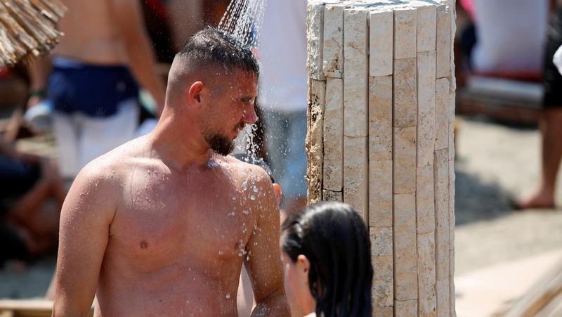 Orang-orang menikmati laut di perairan dangkal saat suhu mendekati 40 derajat Celsius di Ulcinj, Montenegro, 13 Agustus 2024. (REUTERS/Stevo Vasiljevic)