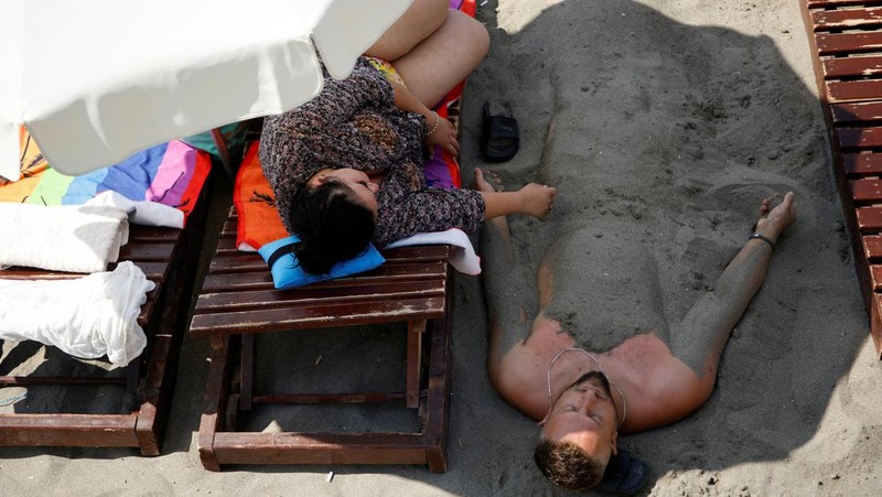 Orang-orang menikmati laut di perairan dangkal saat suhu mendekati 40 derajat Celsius di Ulcinj, Montenegro, 13 Agustus 2024. (REUTERS/Stevo Vasiljevic)