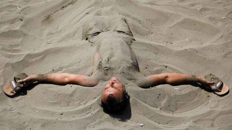Orang-orang menikmati laut di perairan dangkal saat suhu mendekati 40 derajat Celsius di Ulcinj, Montenegro, 13 Agustus 2024. (REUTERS/Stevo Vasiljevic)