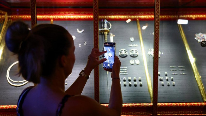 Seorang wanita mengambil gambar, saat barang-barang yang ditemukan dari pencurian permata di museum Gruenes Gewoelbe (Gudang Hijau) pada tahun 2019 dengan perkiraan nilai lebih dari 113 juta euro kembali dipamerkan setelah restorasi, di Dresden, Jerman, 13 Agustus 2024. (REUTERS/Nadja Wohlleben)