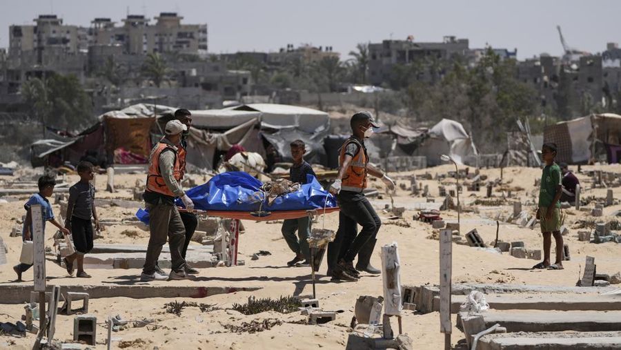 FILE - Workers carry a body, one of more than 80 bodies returned by Israel, to a cemetery in Khan Younis, Gaza Strip, Monday, Aug. 5, 2024. (AP Photo/Abdel Kareem Hana, File)