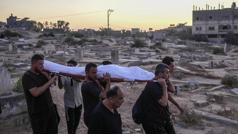 Palestinian mourners carry their loved one for burial at the cemetery in Deir al-Balah, Gaza Strip, Friday, Aug. 9, 2024. (AP Photo/Abdel Kareem Hana)