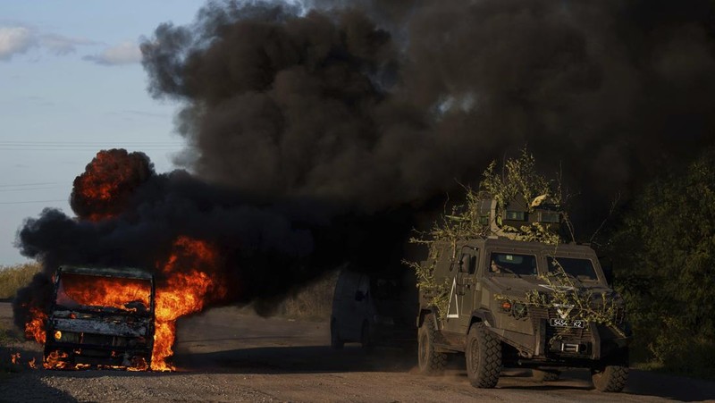 A Ukrainian tank passes by a burning car near the Russian-Ukrainian border, Sumy region, Ukraine, Wednesday, Aug. 14, 2024. (AP Photo/Evgeniy Maloletka)