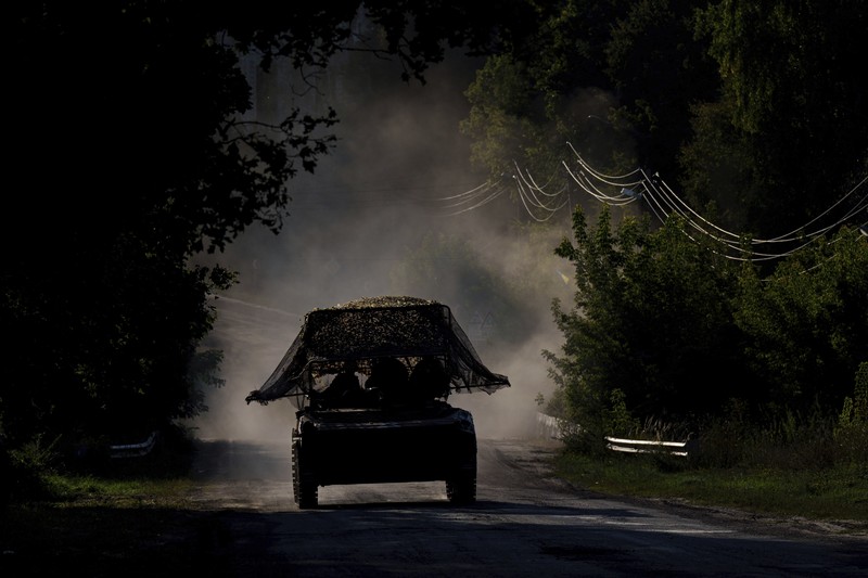 A Ukrainian tank passes by a burning car near the Russian-Ukrainian border, Sumy region, Ukraine, Wednesday, Aug. 14, 2024. (AP Photo/Evgeniy Maloletka)