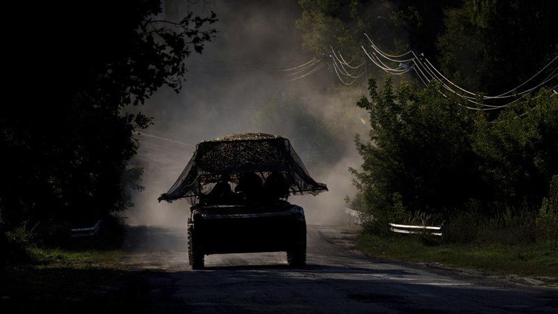 A Ukrainian tank passes by a burning car near the Russian-Ukrainian border, Sumy region, Ukraine, Wednesday, Aug. 14, 2024. (AP Photo/Evgeniy Maloletka)