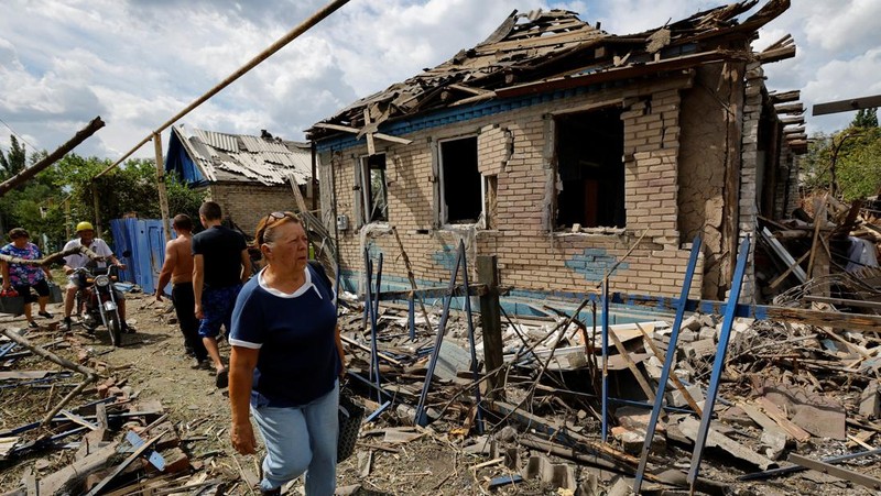 Penduduk setempat berjalan melewati sebuah rumah yang hancur akibat penembakan baru-baru ini, yang oleh otoritas setempat yang dibentuk Rusia disebut sebagai serangan militer Ukraina, selama konflik Rusia-Ukraina di Horlivka (Gorlovka) di wilayah Donetsk, Ukraina yang dikuasai Rusia, 15 Agustus 2024. (REUTERS/Alexander Ermochenko)