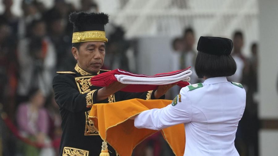 Presiden Indonesia Joko Widodo, kiri, menyerahkan bendera Merah Putih kepada pembawa untuk dikibarkan selama upacara peringatan HUT ke-79 kemerdekaan Indonesia di Istana Negara, Ibu Kota Nusantara (IKN), Kalimantan Timur, Sabtu (17/8/2024). (AP Photo/Achmad Ibrahim)