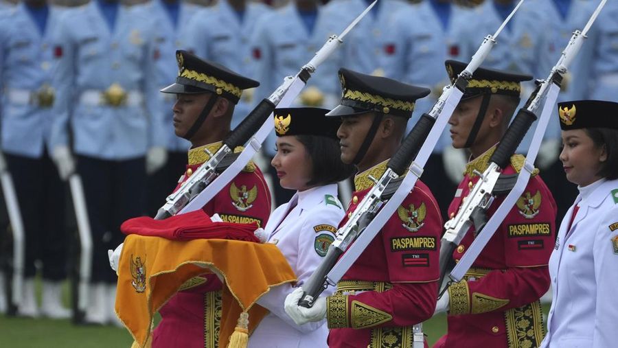 Seorang pembawa bendera dikawal oleh anggota pasukan kehormatan saat membawa bendera nasional Merah Putih yang akan dikibarkan selama upacara peringatan HUT ke-79 kemerdekaan Indonesia di Istana Negara, Ibu Kota Nusantara (IKN), Kalimantan Timur, Sabtu (17/8/2024). (AP Photo/Achmad Ibrahim)