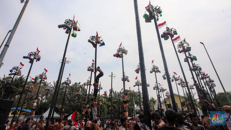 Warga mengikuti lomba panjat pinang kolosal dalam rangka HUT Ke-79 Kemerdekaan RI di Pantai Ancol, Jakarta, Sabtu (17/8/2024). (CNBC Indonesia/Faisal Rahman)