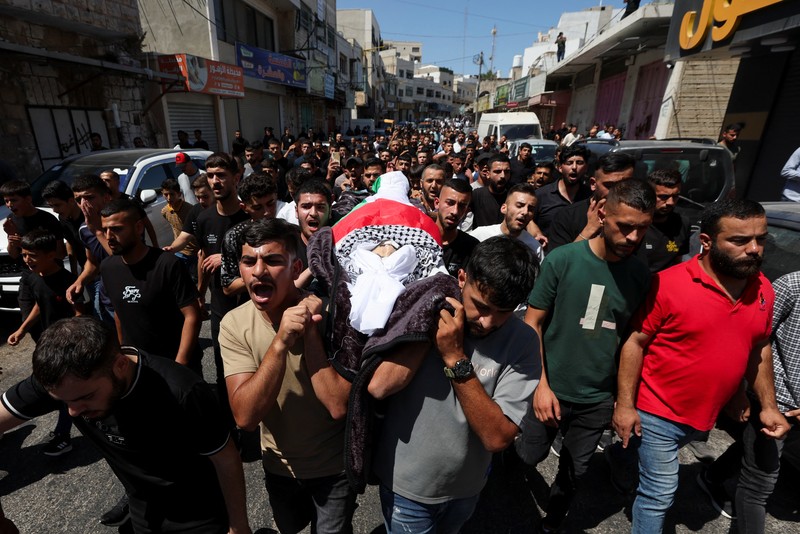 Para pelayat membawa jenazah seorang warga Palestina berusia 18 tahun saat prosesi pemakaman di Dura, Tepi Barat, Selasa (20/8/2024). (REUTERS/Mussa Qawasma)