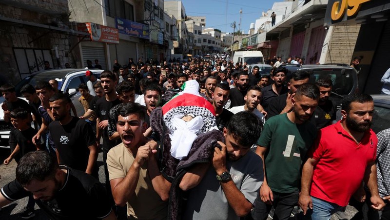 Para pelayat membawa jenazah seorang warga Palestina berusia 18 tahun saat prosesi pemakaman di Dura, Tepi Barat, Selasa (20/8/2024). (REUTERS/Mussa Qawasma)