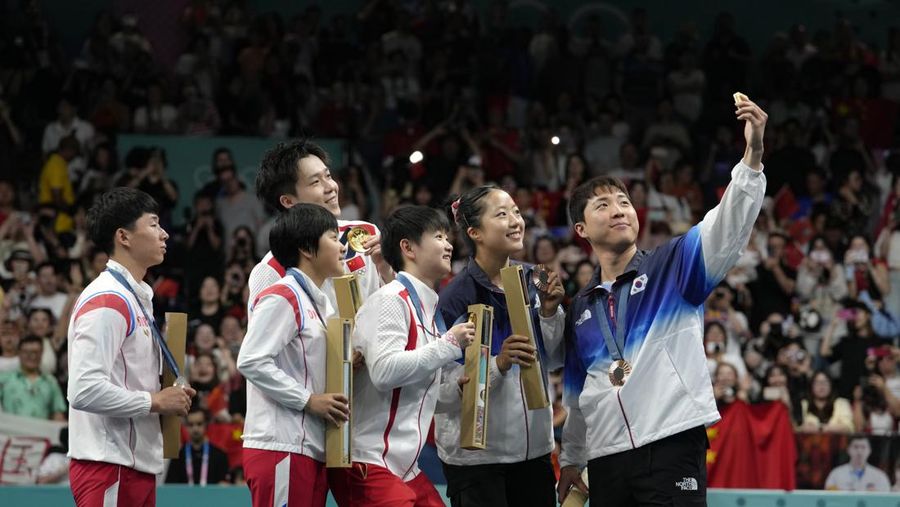 Lim Jonghoon dari Korea Selatan, kanan, berswafoto dengan Ri Jong Sik dari Korea Utara, kiri, dan Kim Kum, kedua dari kiri, Wang Chuqin dari China, latar belakang, dan Sun Yingsha, tengah, serta rekan setimnya Shin Yubin, kanan, dan Lim Jonghoon selama upacara penyerahan medali di Olimpiade Musim Panas 2024, 30 Juli,2024, in Paris, France. (AP Photo/Petros Giannakouris)