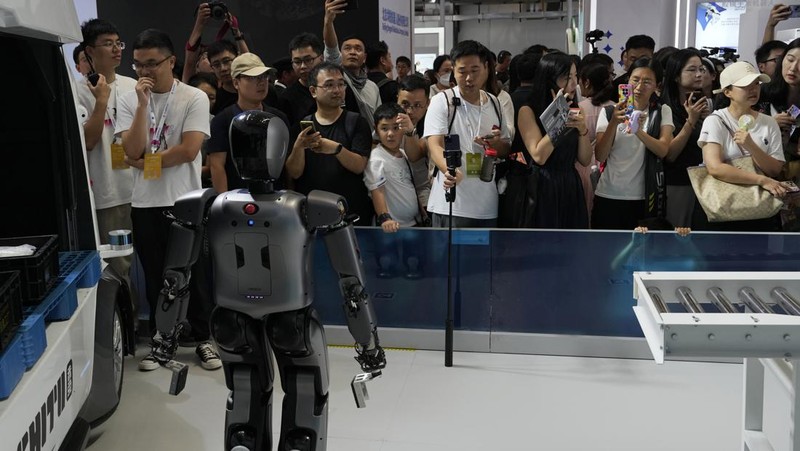 Seorang pekerja berjalan melewati berbagai jenis robot mirip manusia di Konferensi Robot Dunia yang diadakan di Beijing, Rabu, 21 Agustus 2024. (AP Photo/Ng Han Guan)