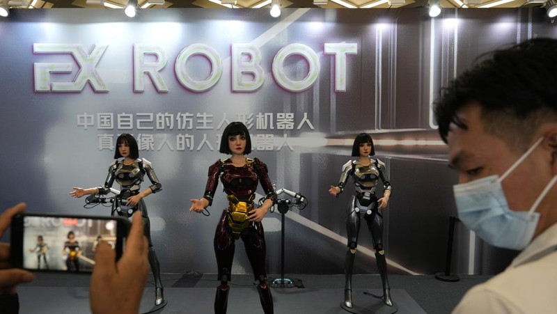 Seorang pekerja berjalan melewati berbagai jenis robot mirip manusia di Konferensi Robot Dunia yang diadakan di Beijing, Rabu, 21 Agustus 2024. (AP Photo/Ng Han Guan)