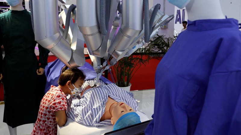 Seorang pekerja berjalan melewati berbagai jenis robot mirip manusia di Konferensi Robot Dunia yang diadakan di Beijing, Rabu, 21 Agustus 2024. (AP Photo/Ng Han Guan)