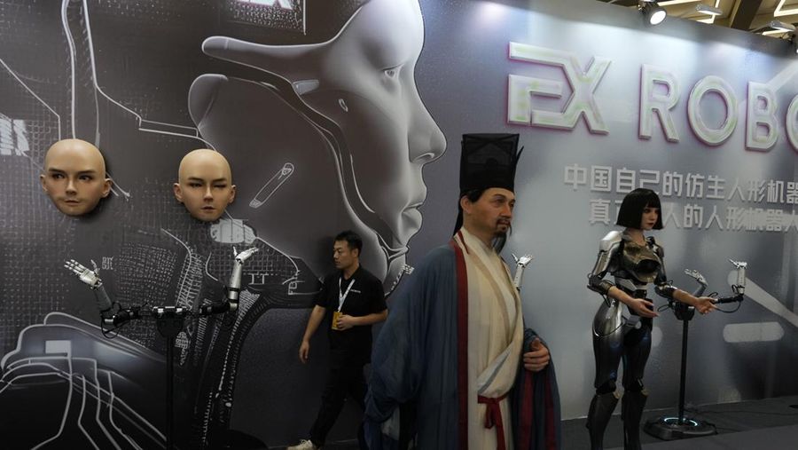 Seorang pekerja berjalan melewati berbagai jenis robot mirip manusia di Konferensi Robot Dunia yang diadakan di Beijing, Rabu, 21 Agustus 2024. (AP Photo/Ng Han Guan)
