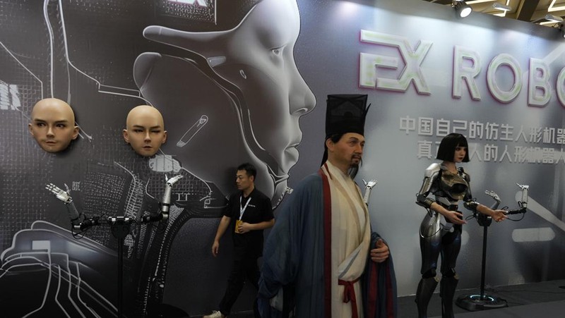 Seorang pekerja berjalan melewati berbagai jenis robot mirip manusia di Konferensi Robot Dunia yang diadakan di Beijing, Rabu, 21 Agustus 2024. (AP Photo/Ng Han Guan)