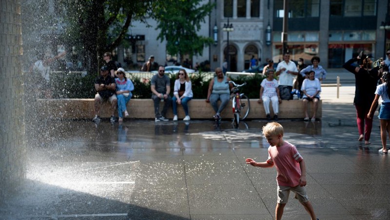 Seorang wanita menggunakan payung untuk melindungi dirinya dari sinar matahari selama cuaca panas di Chicago, Illinois, AS, 26 Agustus 2024. (REUTERS/Vincent Alban)