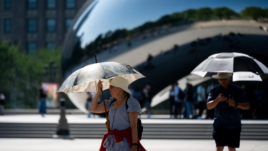 Seorang wanita menggunakan payung untuk melindungi dirinya dari sinar matahari selama cuaca panas di Chicago, Illinois, AS, 26 Agustus 2024. (REUTERS/Vincent Alban)