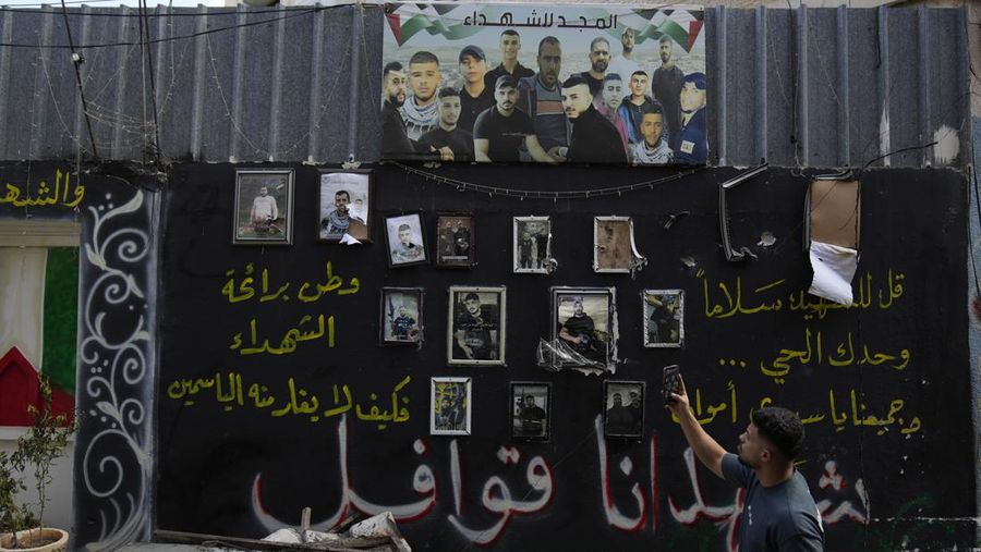 A man takes a picture of a wall displaying photos of Palestinians, who died during previous clashes, following an Israeli military operation in the West Bank refugee camp of Al-Faraa, Thursday, Aug. 29, 2024. (AP Photo/Nasser Nasser)