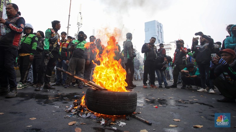Sejumlah pengemudi ojek online melakukan bakar ban saat aksi unjuk rasa di kawasan Patung Kuda Arjuna Wijaya, Jakarta, Kamis (29/8/2024). (CNBC Indonesia/Faisal Rahman)