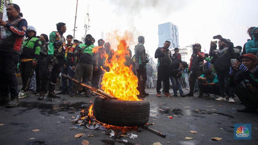 Sejumlah pengemudi ojek online melakukan bakar ban saat aksi unjuk rasa di kawasan Patung Kuda Arjuna Wijaya, Jakarta, Kamis (29/8/2024). (CNBC Indonesia/Faisal Rahman)