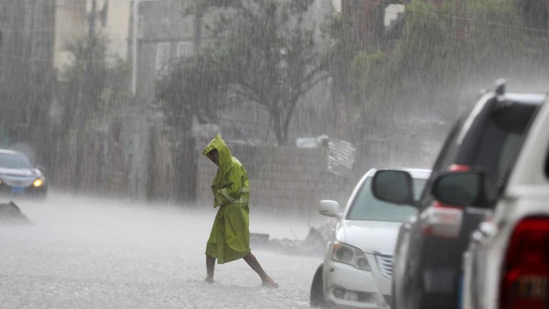 Seorang pria menyeberangi jalan yang banjir saat hujan lebat di Sanaa, Yaman, 28 Agustus 2024. (REUTERS/Khaled Abdullah)