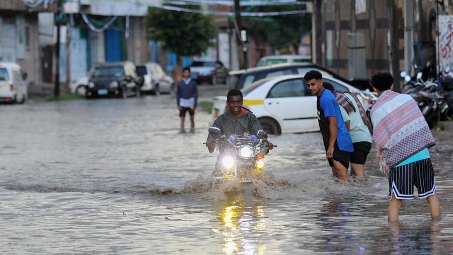 Seorang pria menyeberangi jalan yang banjir saat hujan lebat di Sanaa, Yaman, 28 Agustus 2024. (REUTERS/Khaled Abdullah)