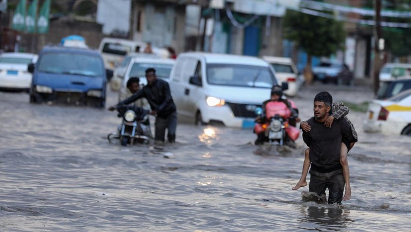 Seorang pria menyeberangi jalan yang banjir saat hujan lebat di Sanaa, Yaman, 28 Agustus 2024. (REUTERS/Khaled Abdullah)